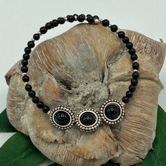 One loop memory wire bracelet made with large Black Onyx beads enclosed in a gold bead frame.