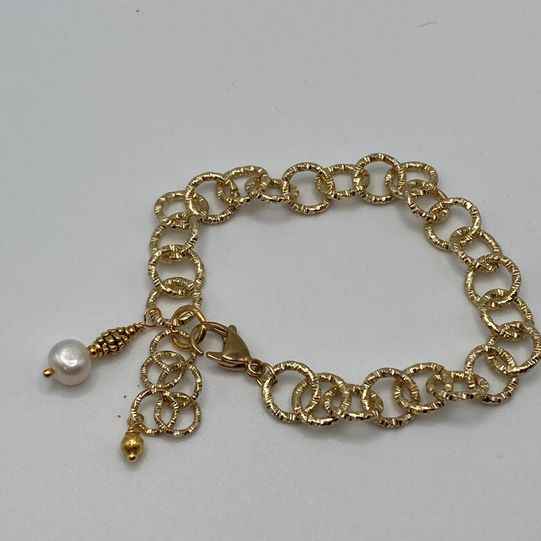 This bracelet is made with a gold tone sparkle chain and accented with a pearl bead dangle.  The bracelet extends to fit up to an 8-inch wrist.  This bracelet pairs nicely with earrings found elsewhere in the collection.