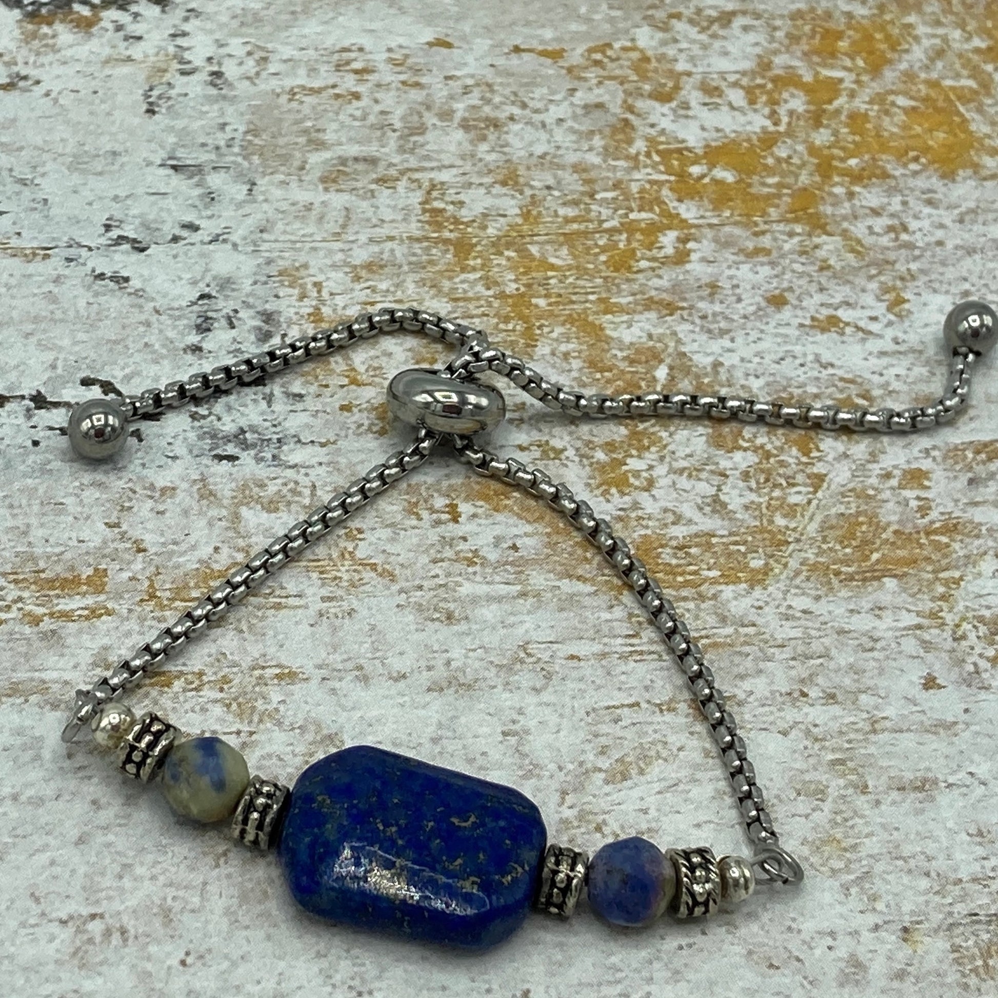 Lapis cube focal bead surrounded by round sodalite beads and antique spacer beads. The bracelet slides on and off and adjusts to individual wrist sizes