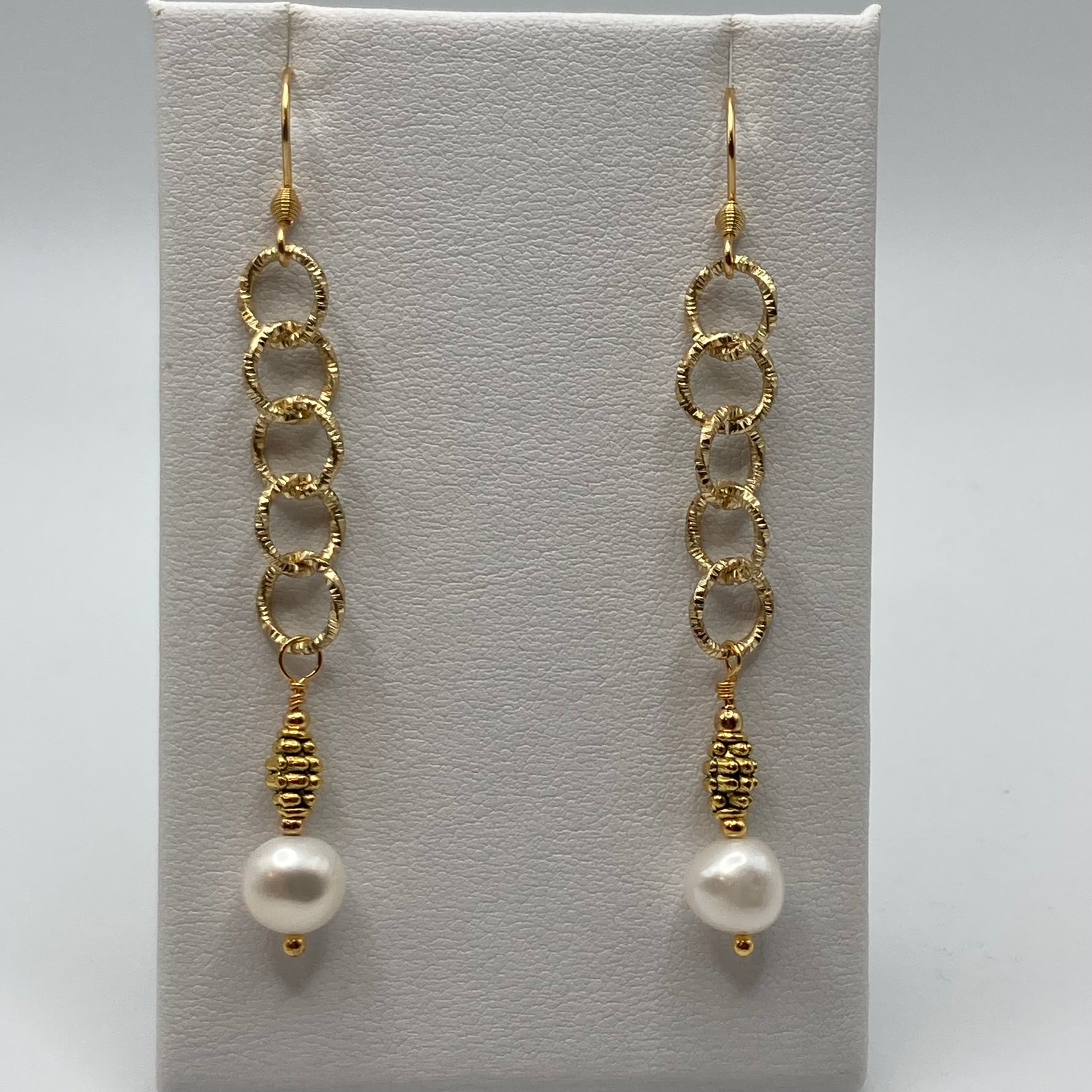 These earrings are made with a  freshwater pearl dangle which is attached to gold-tone chain.  They measure approximately one inch in length.