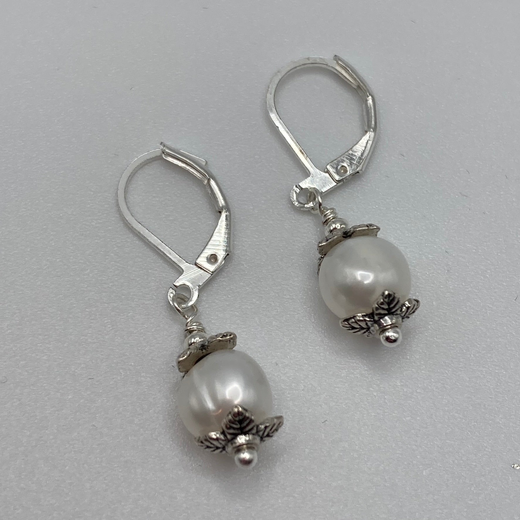 A single pearl accented with silver-tone bead caps are attached to lever back ear wires.  The simplicity of these earrings make them timeless.