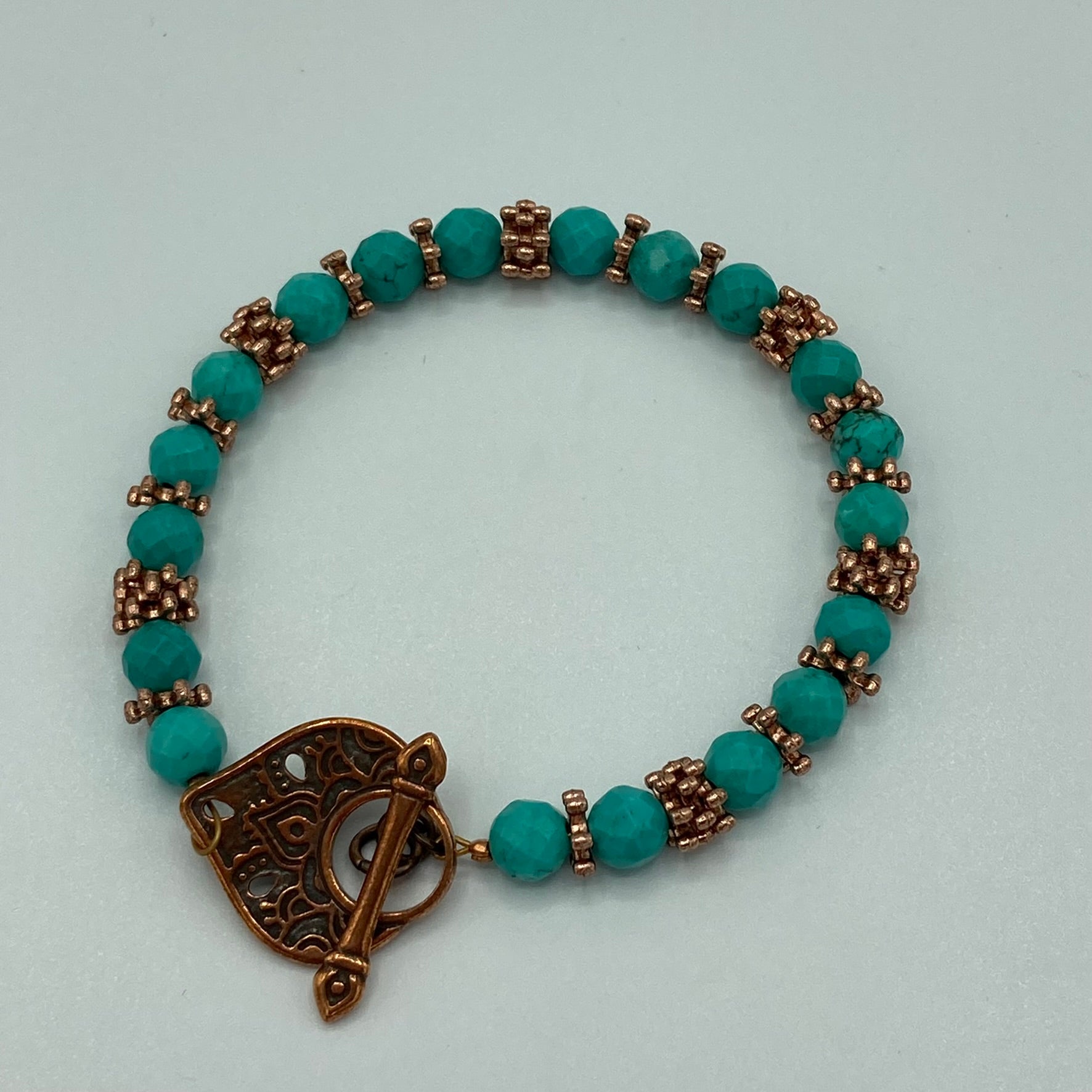 The bracelet is made with 6mm Turquoise faceted round beads, copper daisy spacers, and finished with a Tierra cast antique copper heart-shaped toggle clasp. Fits up to a size 7.5.