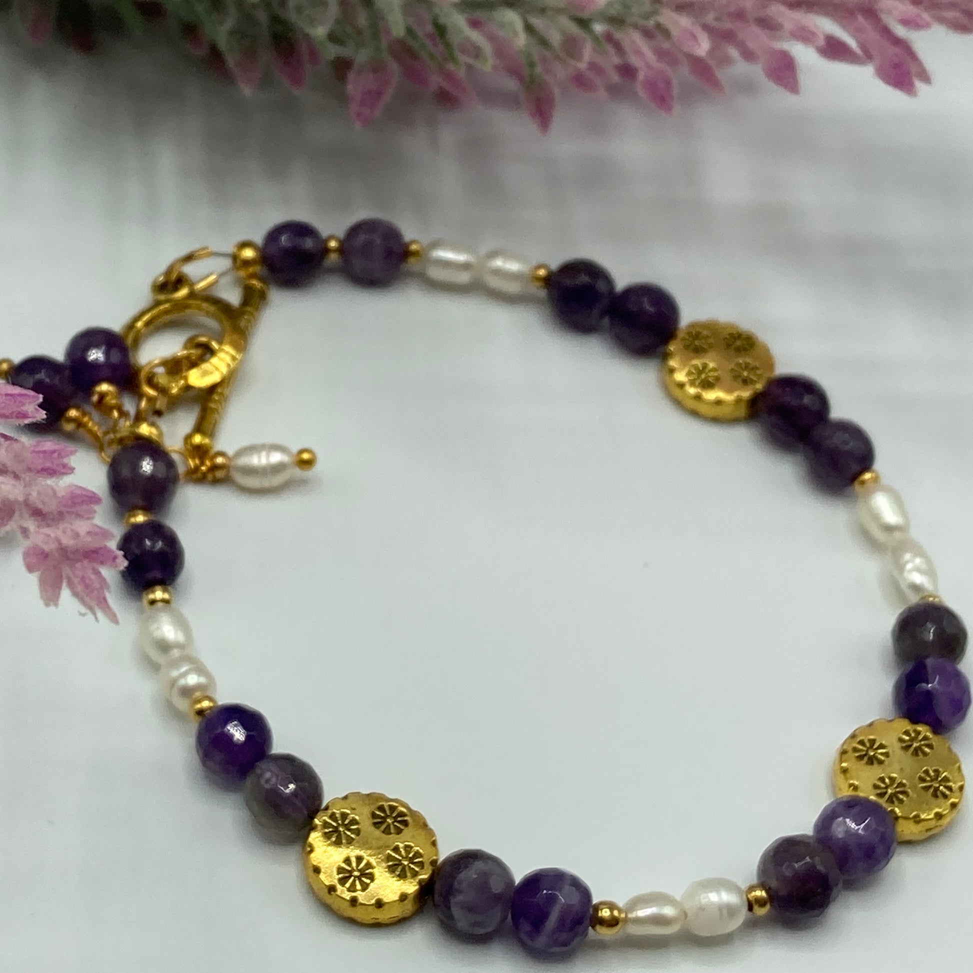 This bracelet is made with 6mm round Amethyst beads, rice pearls, and gold spacer beads and fastens with a gold toggle clasp. Fits up to a size 8