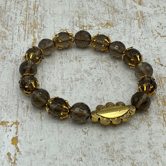 This bracelet is made with Smokey Quartz faceted beads, gold bead caps, and a gold metal accent bead.